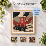 May include: A Kinusaiga art kit featuring a framed square image of a plaid coffee mug resting on a stack of three books. The kit includes foam board and fabric. The text reads KINUSAIGA ART KIT, create warmth with every piece, and Foam Board & fabric Included.