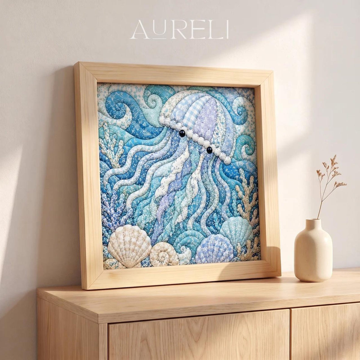 May include: A square framed artwork titled AURELI featuring a quilted-style illustration of a jellyfish in shades of blue, purple, and white. The scene includes swirling water patterns, coral, and seashells at the base, all encased in a light wood frame.