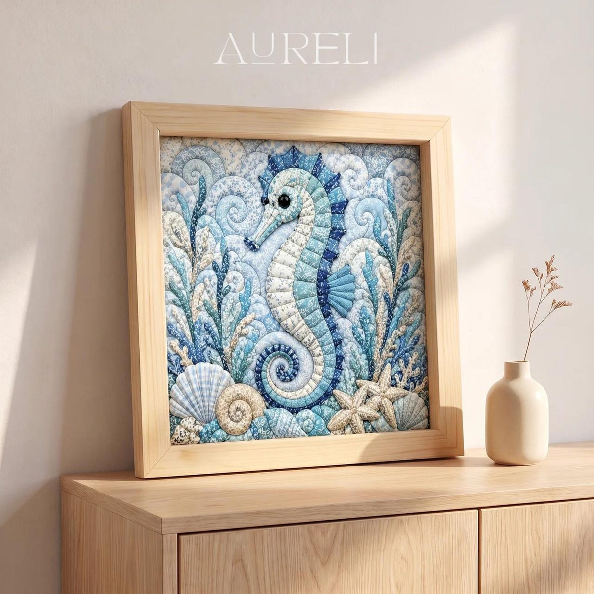 May include: A square framed textile art piece featuring a seahorse surrounded by seashells and coral in shades of blue, white, and beige. The word AURELI is printed in white at the top. The artwork is encased in a light-colored wooden frame.