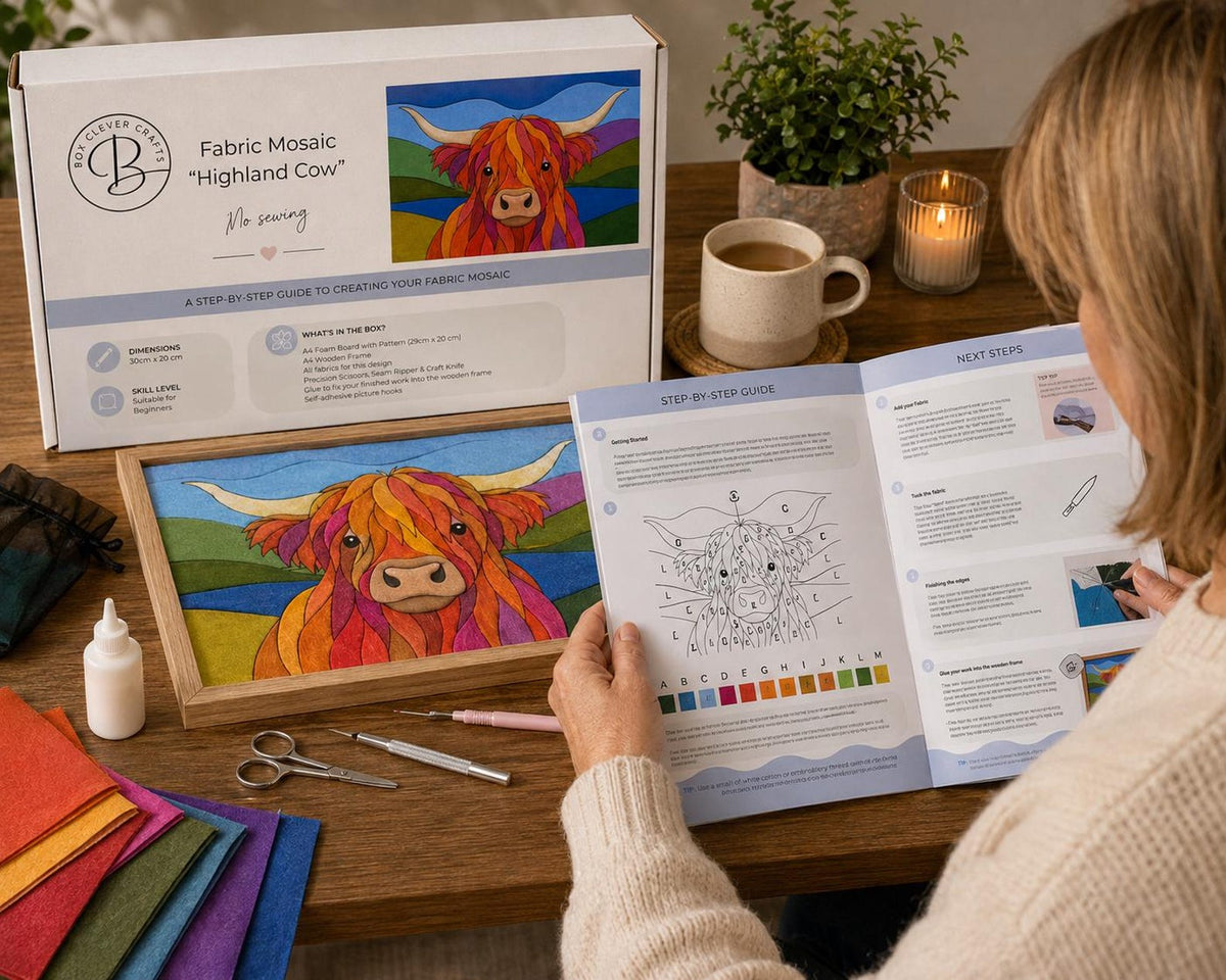 May include: A Box Clever Crafts Highland Cow fabric mosaic kit featuring a white box, a wooden frame with a finished mosaic, a step-by-step instruction booklet, a small white glue bottle, metal scissors, a stylus tool, and colorful fabric swatches.