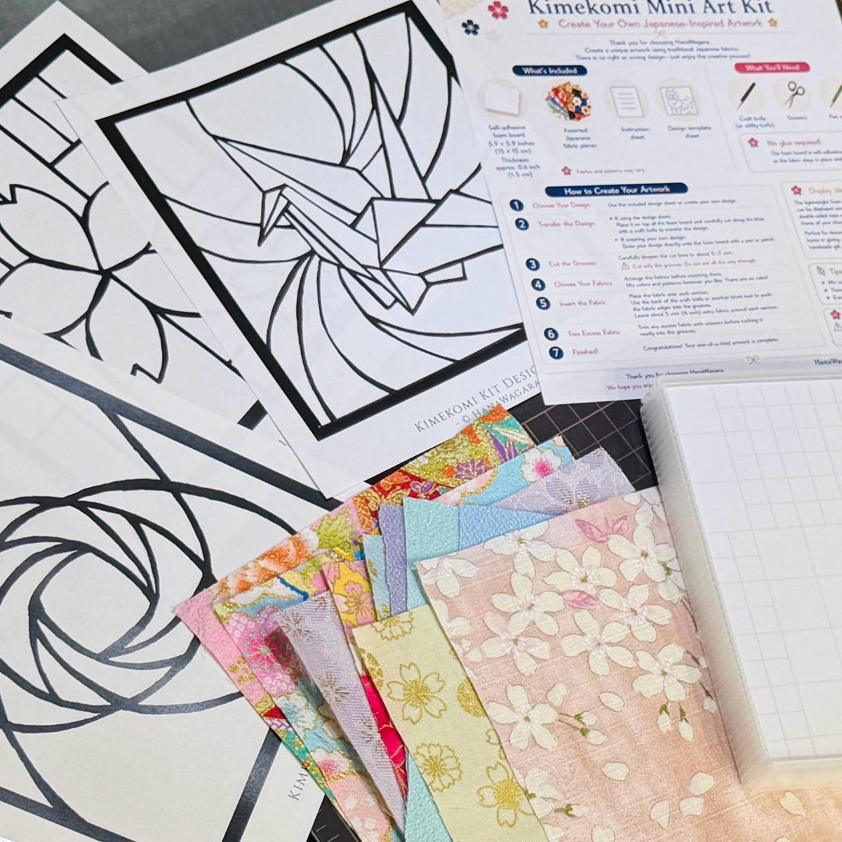 May include: A Kimekomi mini art kit featuring printed design templates of a crane and floral patterns, a set of colorful patterned fabric swatches, a white adhesive foam board, and an instructional sheet with step-by-step assembly guides.
