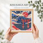 May include: A square Kinusaiga art kit featuring a framed fabric collage of Mount Fuji, a red torii gate, and a large red sun. The artwork displays intricate floral patterns in shades of blue, red, and cream, with the text KINUSAIGA ART KIT.
